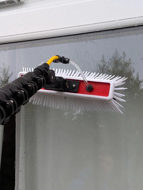 Close-up of water-fed pole brush on window